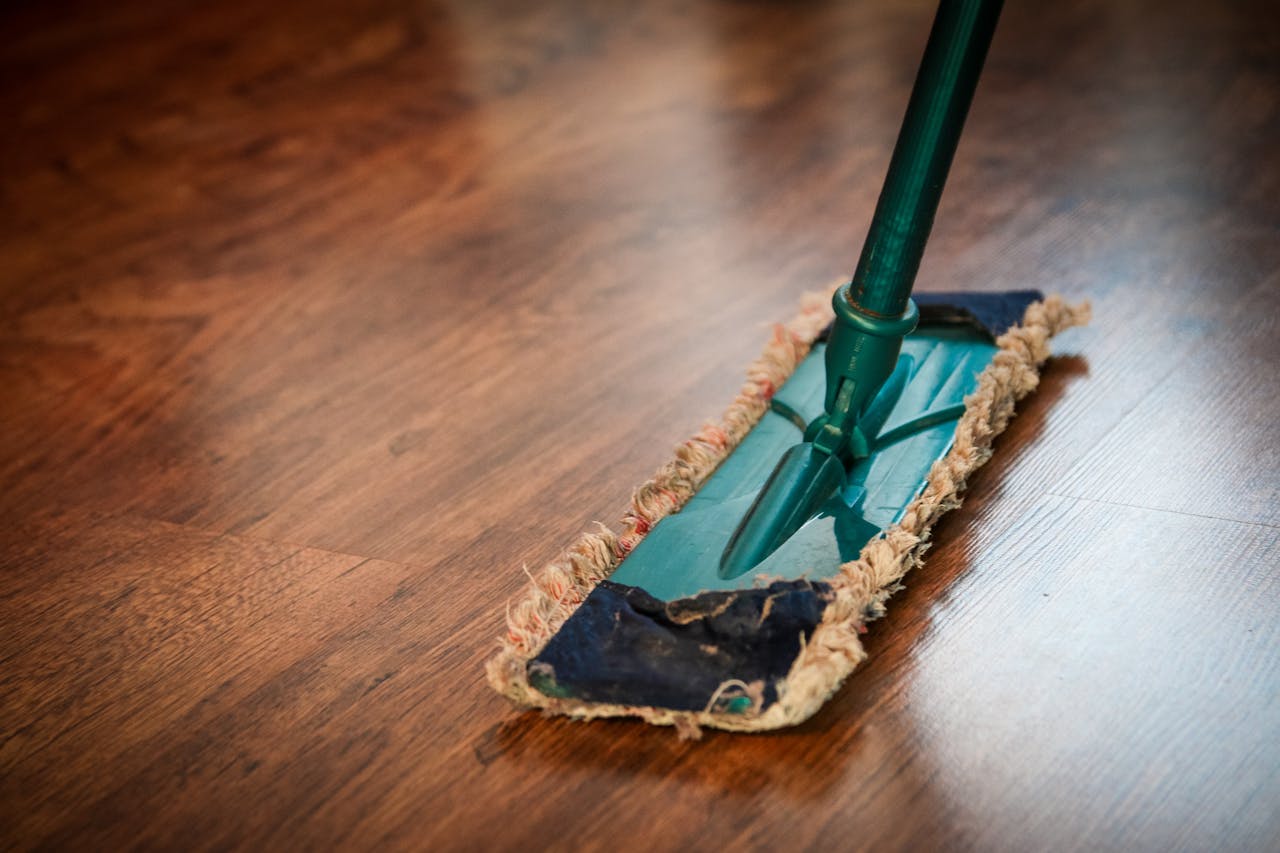 expertise-01 A detailed view of a mop cleaning a wooden floor, showing texture and pattern.